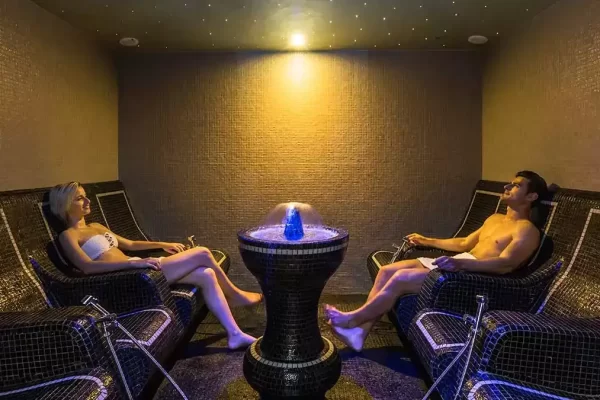 Ein Mann und eine Frau entspannen sich auf Liegen in einem stilvollen Wellnessraum.